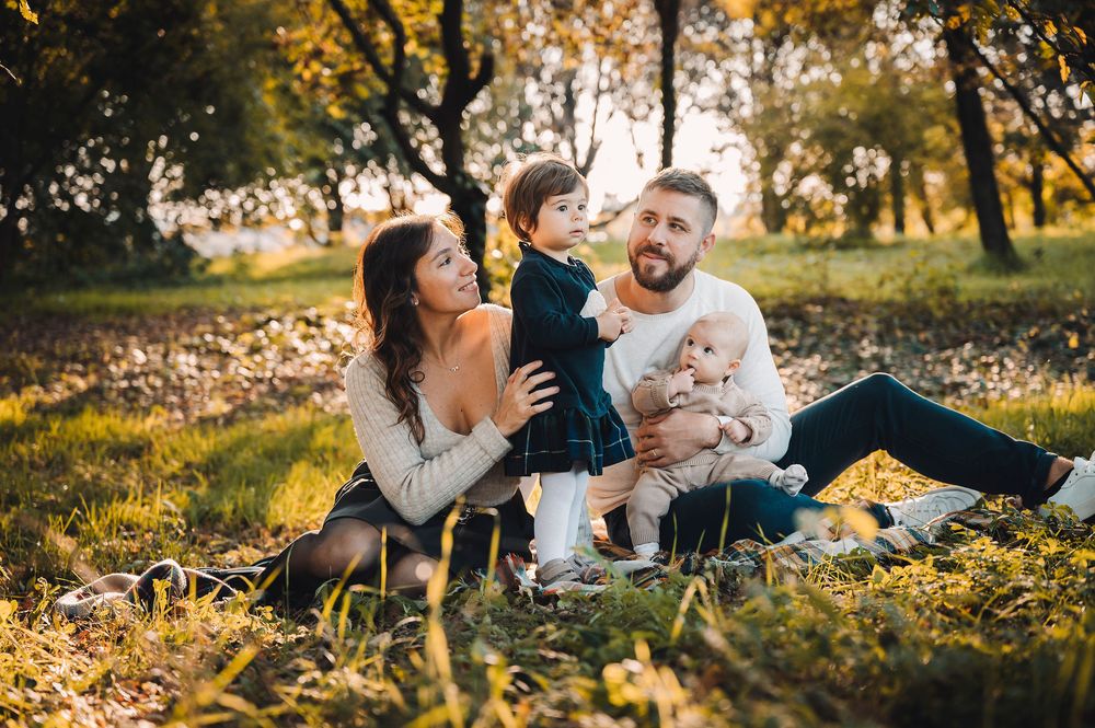 Una calda sessione fotografica di famiglia al tramonto in un parco con foglie autunnali, a Padova.