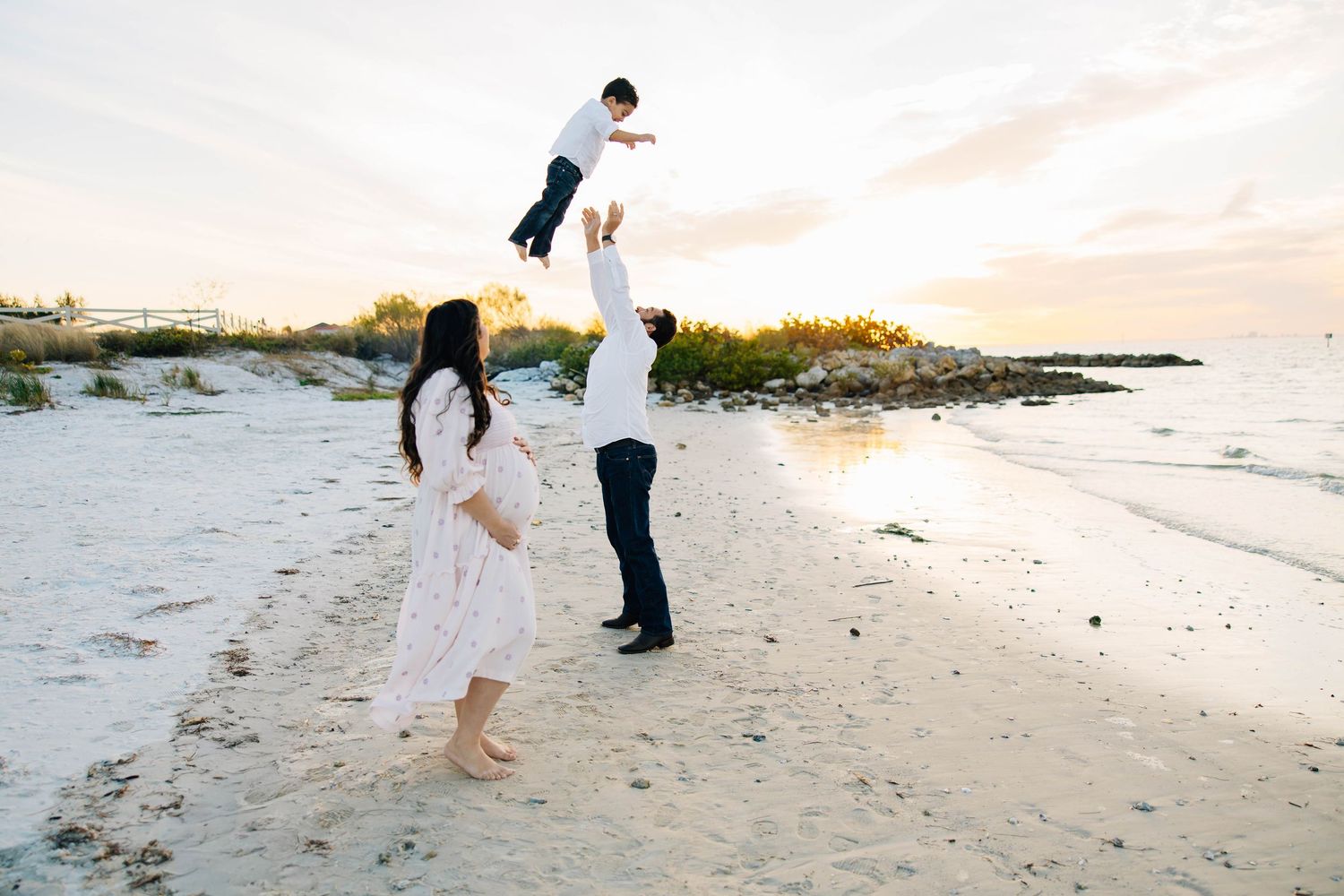 Lifestyle family session capturing parents and children running and playing together on the beach at sunset.
