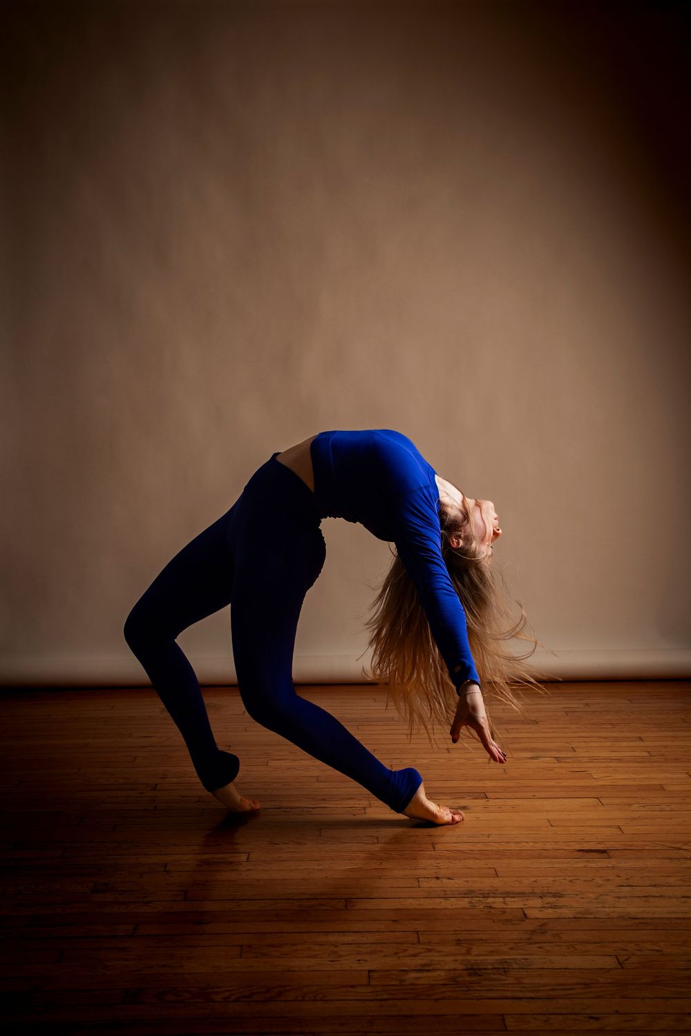 A dancer performs a graceful backbend sequence on a wooden floor, captured in a series of progressive movements.