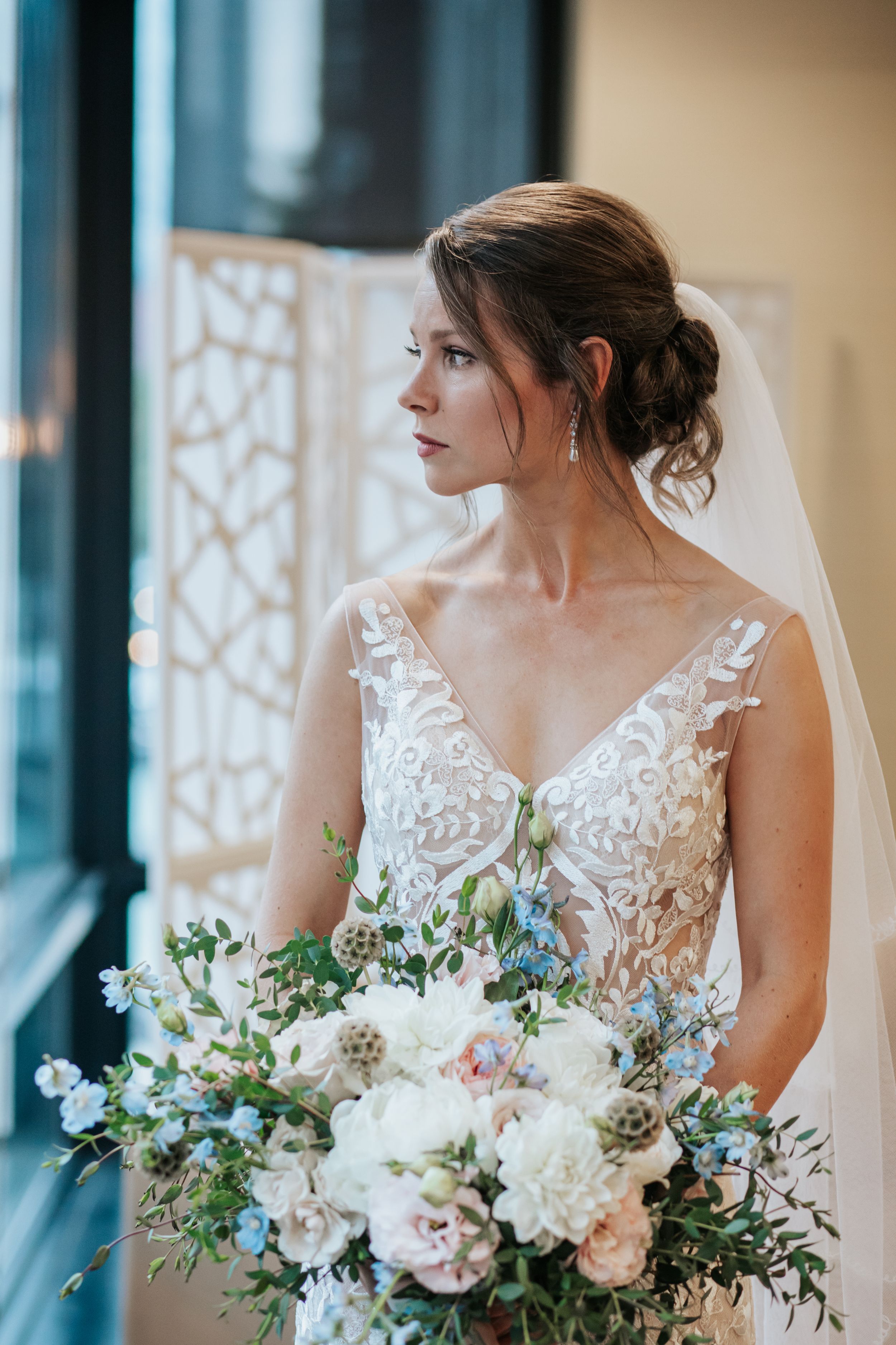 Close up of a beautiful bridal bouquet with white and blush flowers against a window backdrop.