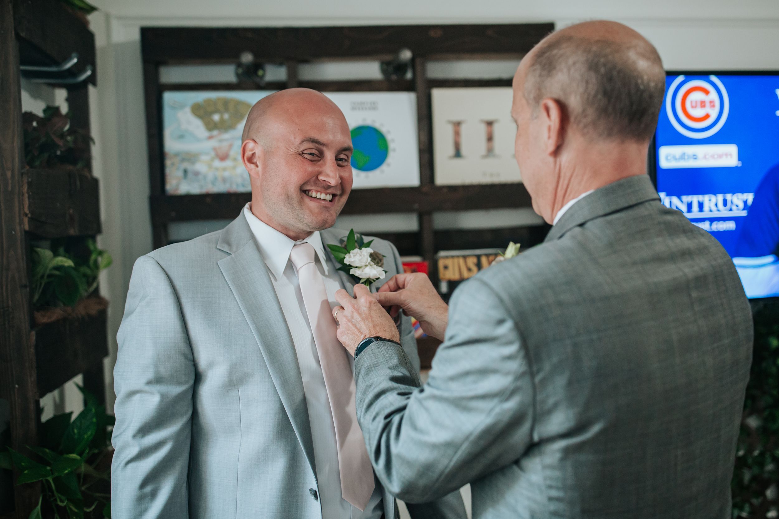 Two men in business attire share a lighthearted moment in an office setting.