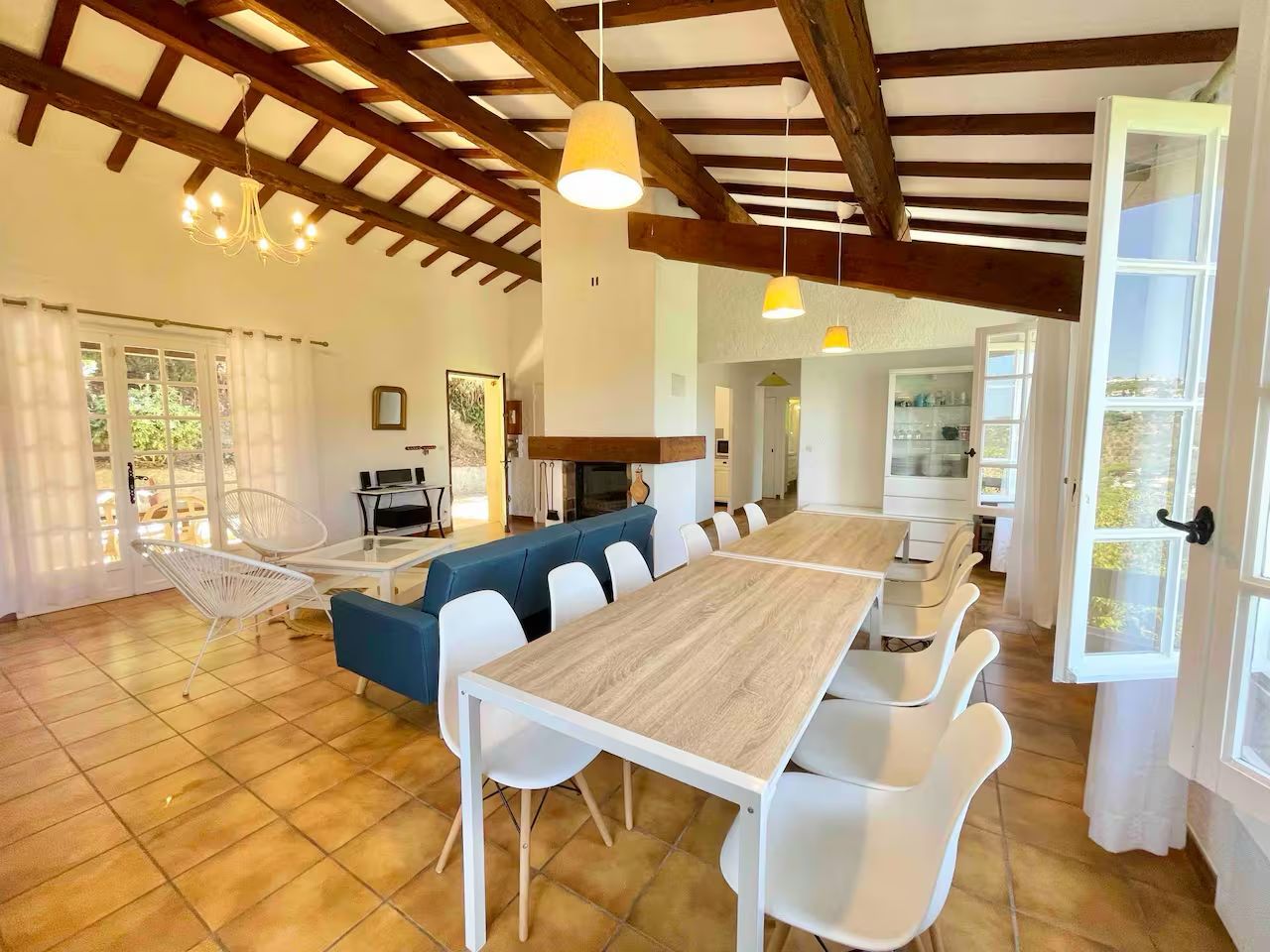 Modern open office space with exposed wooden beams, white furniture and natural lighting through large windows.