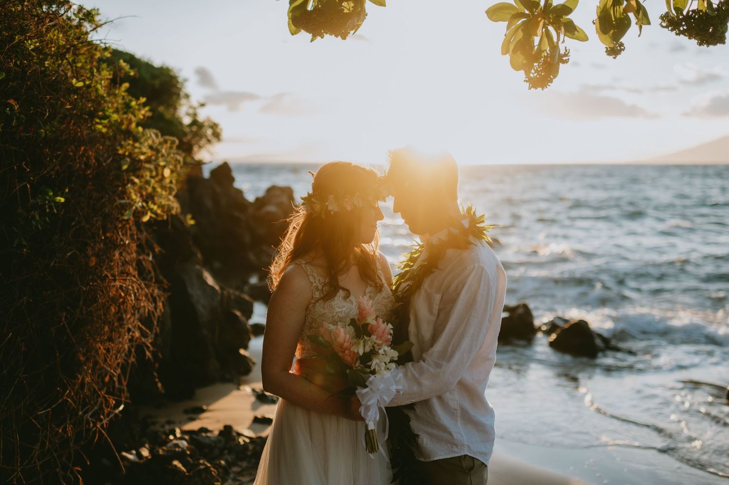 Sunset beach wedding ceremony with golden light filtering through palm trees.