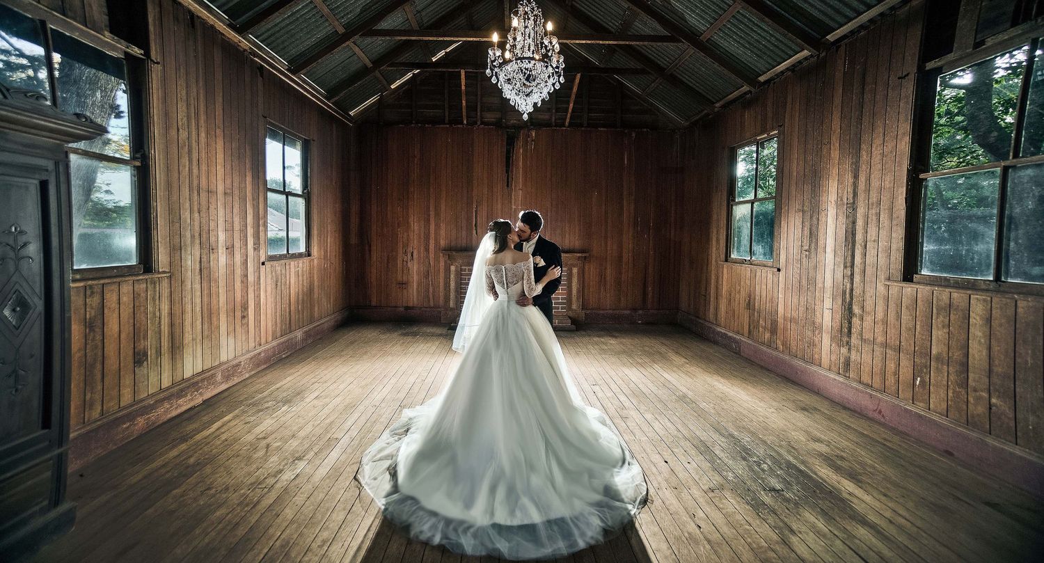 Bride and groom share an intimate moment inside a rustic wooden chapel with chandelier.