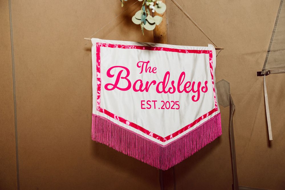Pink and white decorative banners with fringe trim hang from a brown wall in a row.