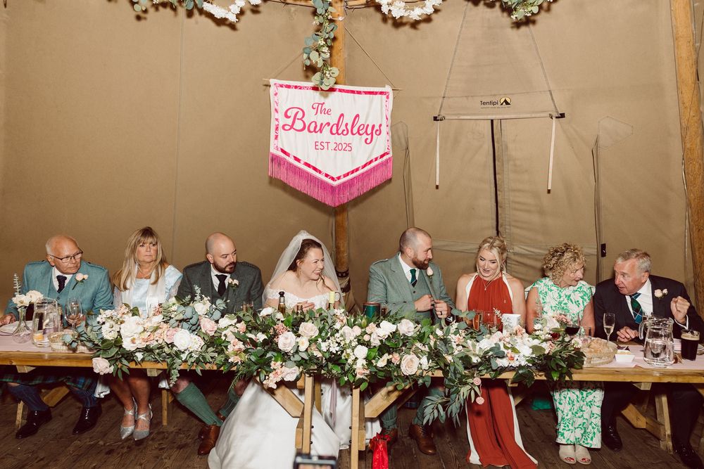 A wedding reception banquet hall decorated with teal and pink accents features tables set for dining with floral centerpieces.