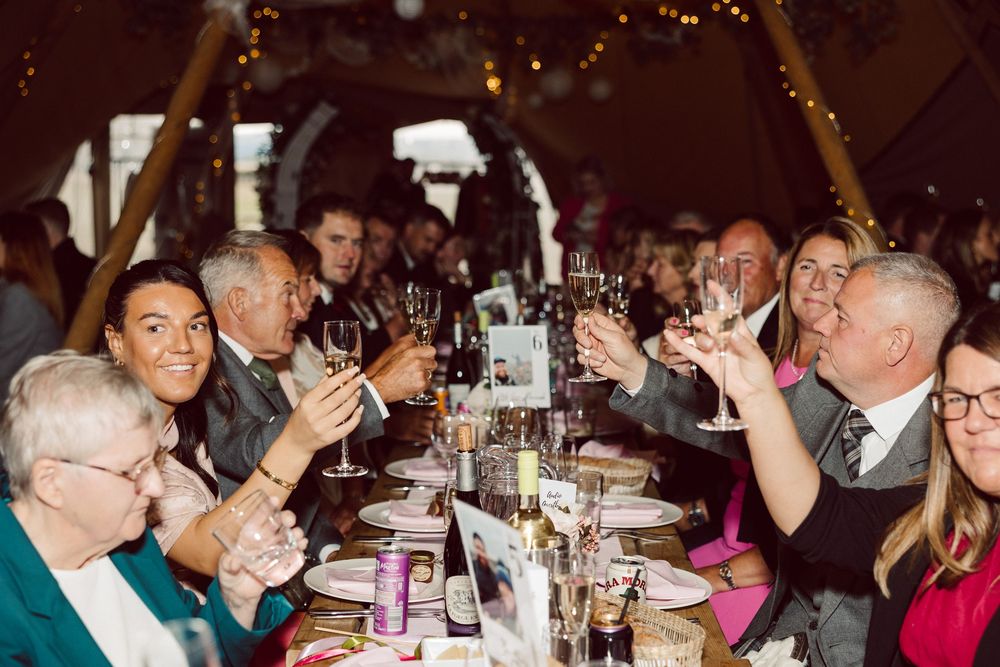 People enjoying drinks and conversation at a crowded social gathering in a dimly lit venue.