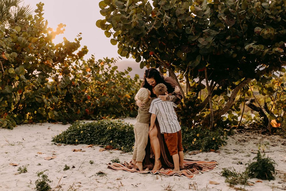 Candid beach scene with people relaxing on sandy shore surrounded by lush greenery.