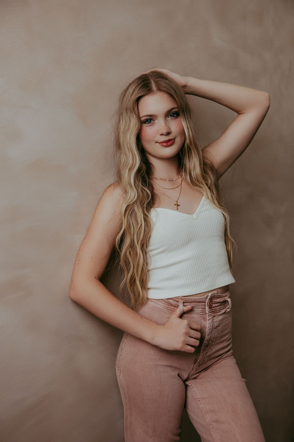 A series of fashion portraits showing a model in a white tank top and dusty rose pants against a neutral backdrop.