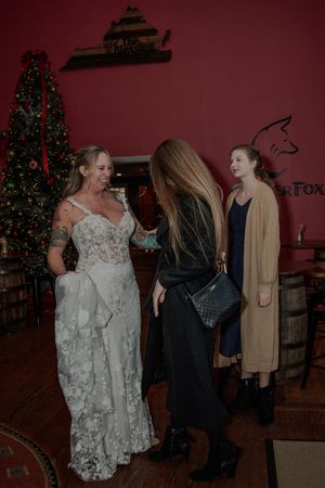A dimly lit indoor space with a decorated Christmas tree and people gathered in formal attire.