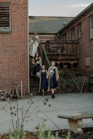 A group descends outdoor stairs at a brick building with a wooden deck and railing.