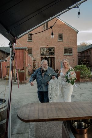 A wedding celebration outside a brick building with people sharing a joyful moment under an outdoor overhang.
