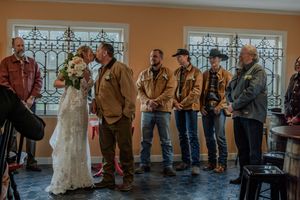Wedding guests gather in a line during a reception celebration at an indoor venue.