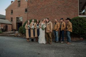 Wedding party in formal attire poses together outside a brick building in a casual group photo series.