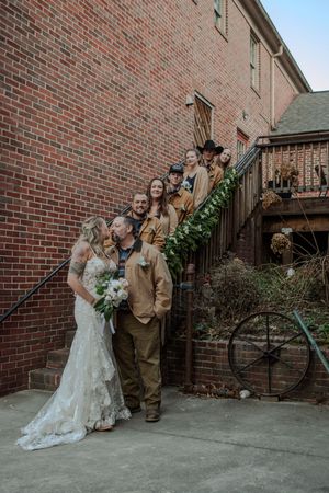 Wedding couple posing for photos against a brick wall exterior with metal railings.
