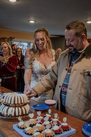 Wedding celebration with bundt cakes and desserts being served on a table surrounded by guests.