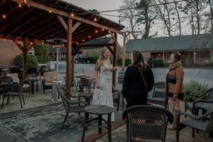 People gather under a wooden pergola with string lights at an outdoor event space.