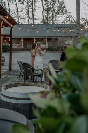 Outdoor wedding venue with string lights and stone fire pits surrounded by chairs at dusk.