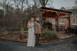 A panoramic view of a rustic wedding venue with string lights and bare trees in winter.