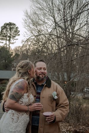 Intimate outdoor wedding moment captured against a backdrop of bare winter trees and natural scenery.