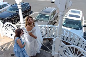 A group plays foosball at an outdoor table while cars are parked in the background on a sunny day.