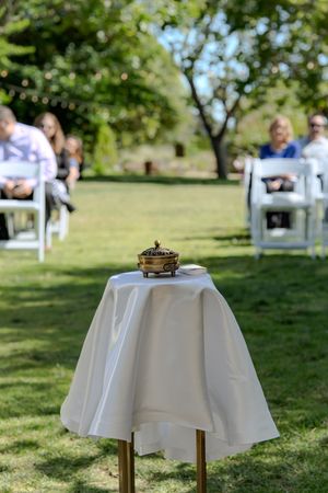 Small decorative box sits atop white tablecloth-covered stand at outdoor garden wedding ceremony.