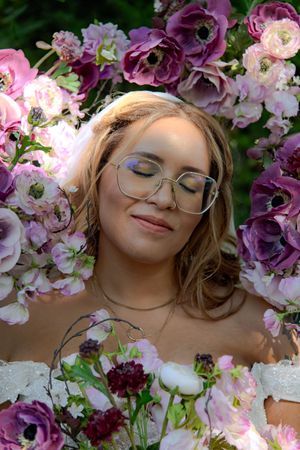 Dreamy portrait surrounded by pink and purple flowers in a romantic garden setting.