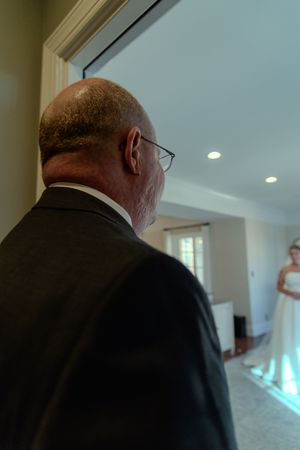 A sequence of photos showing someone in a black suit from behind as they walk through a bright white interior space.