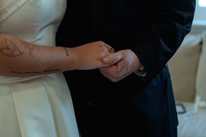 A group of people in dark formal attire standing close together with their hands clasped in front of them.
