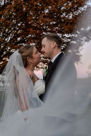 A romantic sequence of wedding photos showing a couple embracing under autumn trees at sunset.