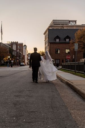 A sequence showing a bride and groom walking along an urban street at dusk with buildings in the background.