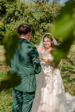 A couple dancing together outdoors surrounded by green foliage on a sunny day.