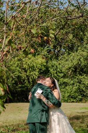A couple shares a romantic embrace in an apple orchard on a sunny autumn day.