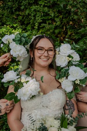 A close-up series of a bride holding a beautiful white rose and eucalyptus bouquet against a lush green garden backdrop.