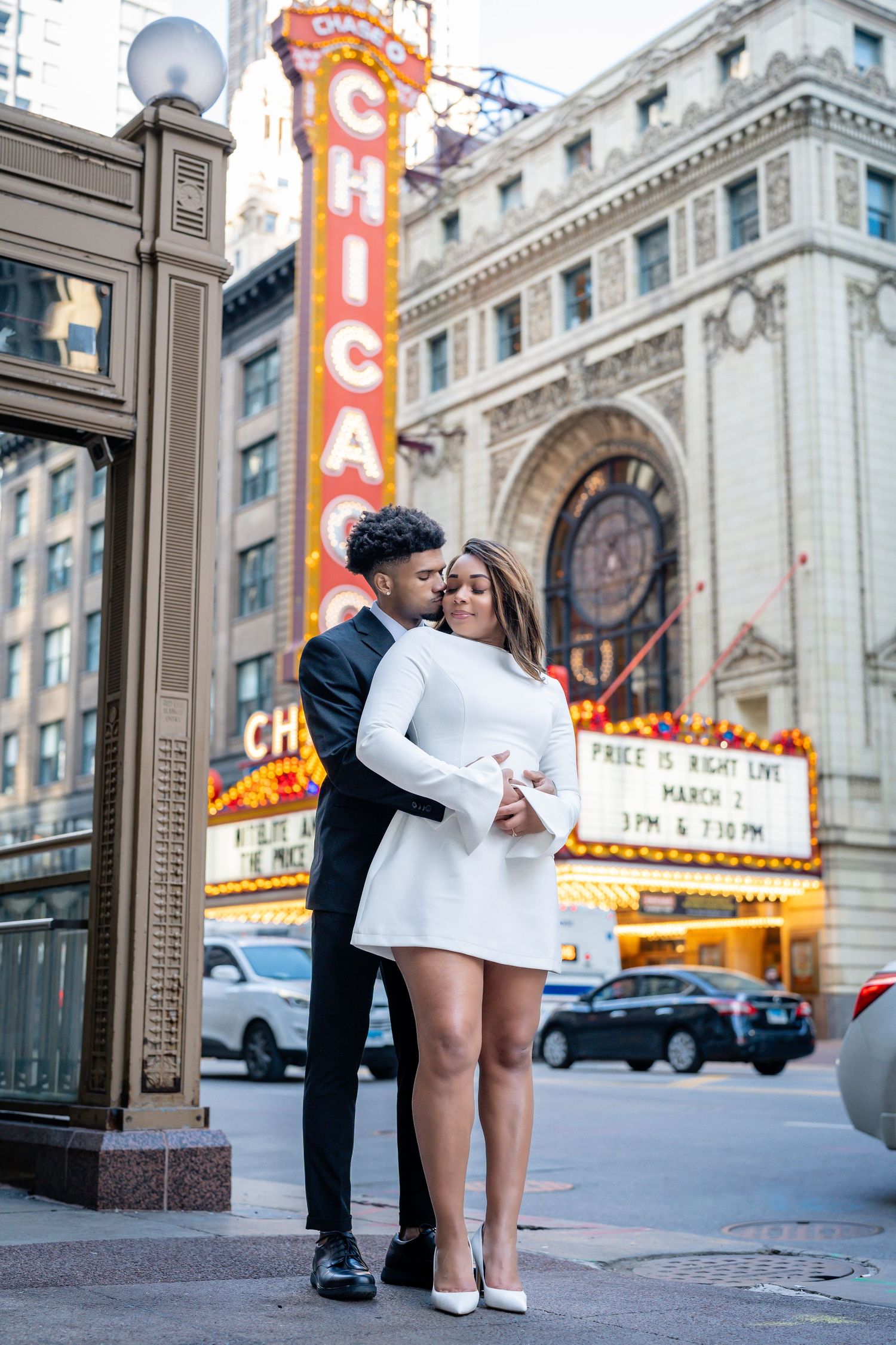 Romantic engagement photo series outside historic Chicago Theater with illuminated marquee sign.