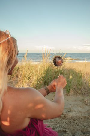 A sequence of images showing someone holding a dandelion against a beach backdrop with ocean and sand dunes.