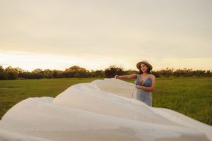 Ethereal scene in a meadow at sunset with flowing white fabric and natural golden light.