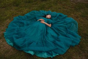 Teal tulle dress with delicate bow detail laid flat on grass in multiple angles.