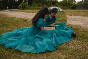 A teal dress flows elegantly across a grassy outdoor setting in a series of artistic photos.