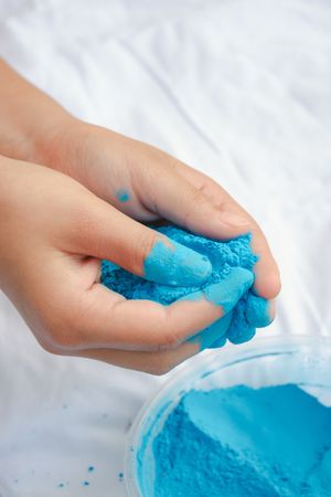 Hands playing with bright blue kinetic sand or play dough showing its moldable texture and vibrant color.