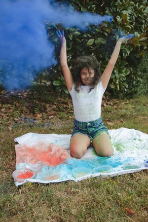 A sequence of colorful powder paint splashes and playful movements on a white sheet in an outdoor setting.