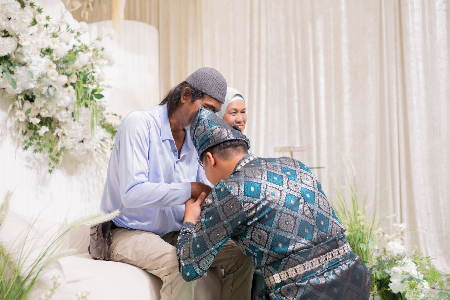 A touching moment between family members during a celebration with floral decorations.