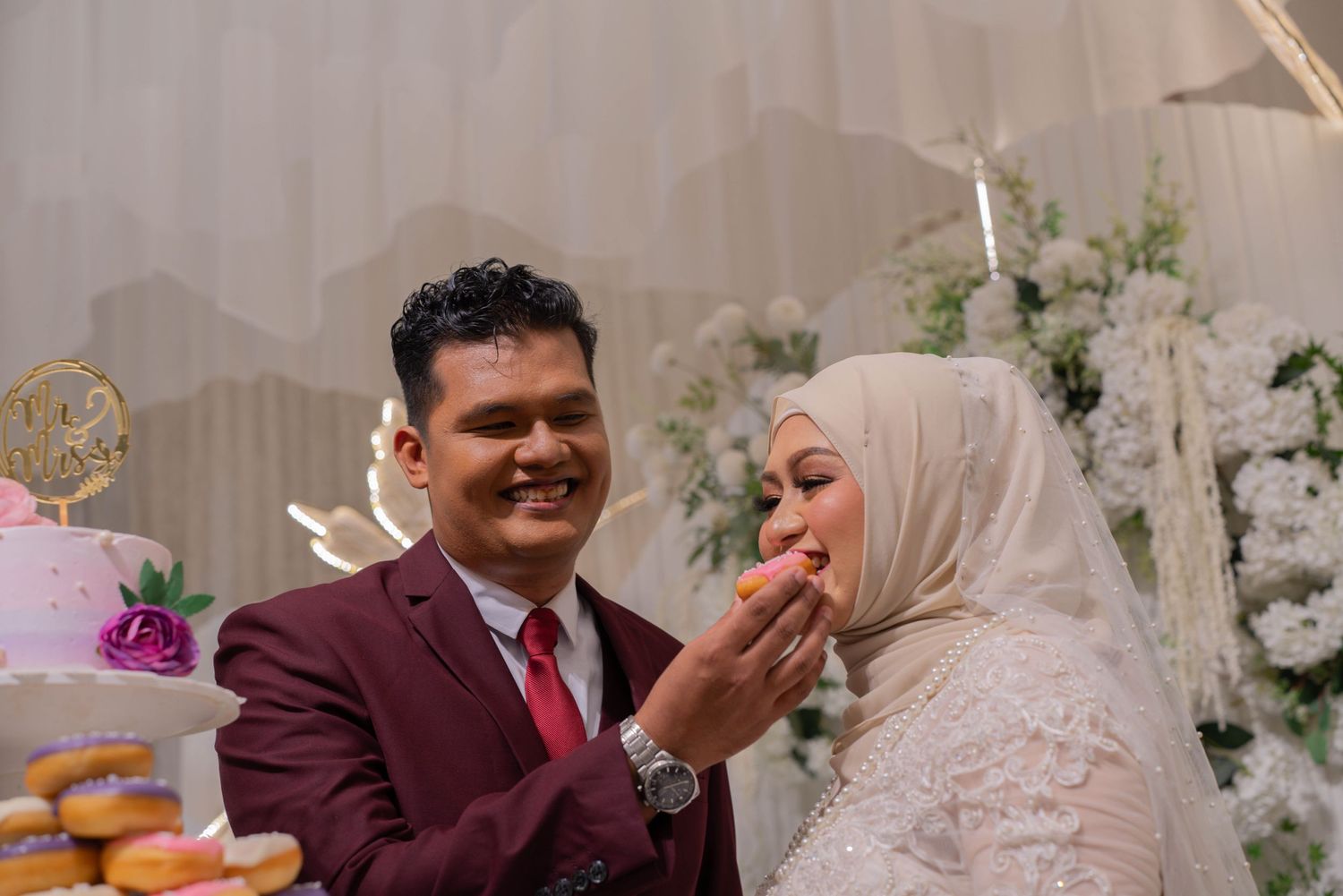 A couple sharing dessert at their wedding reception with floral decorations.