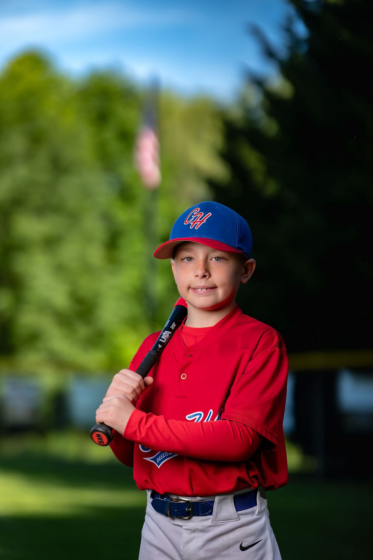 Youth baseball team in blue uniforms poses for official team photo against cloudy sky background.