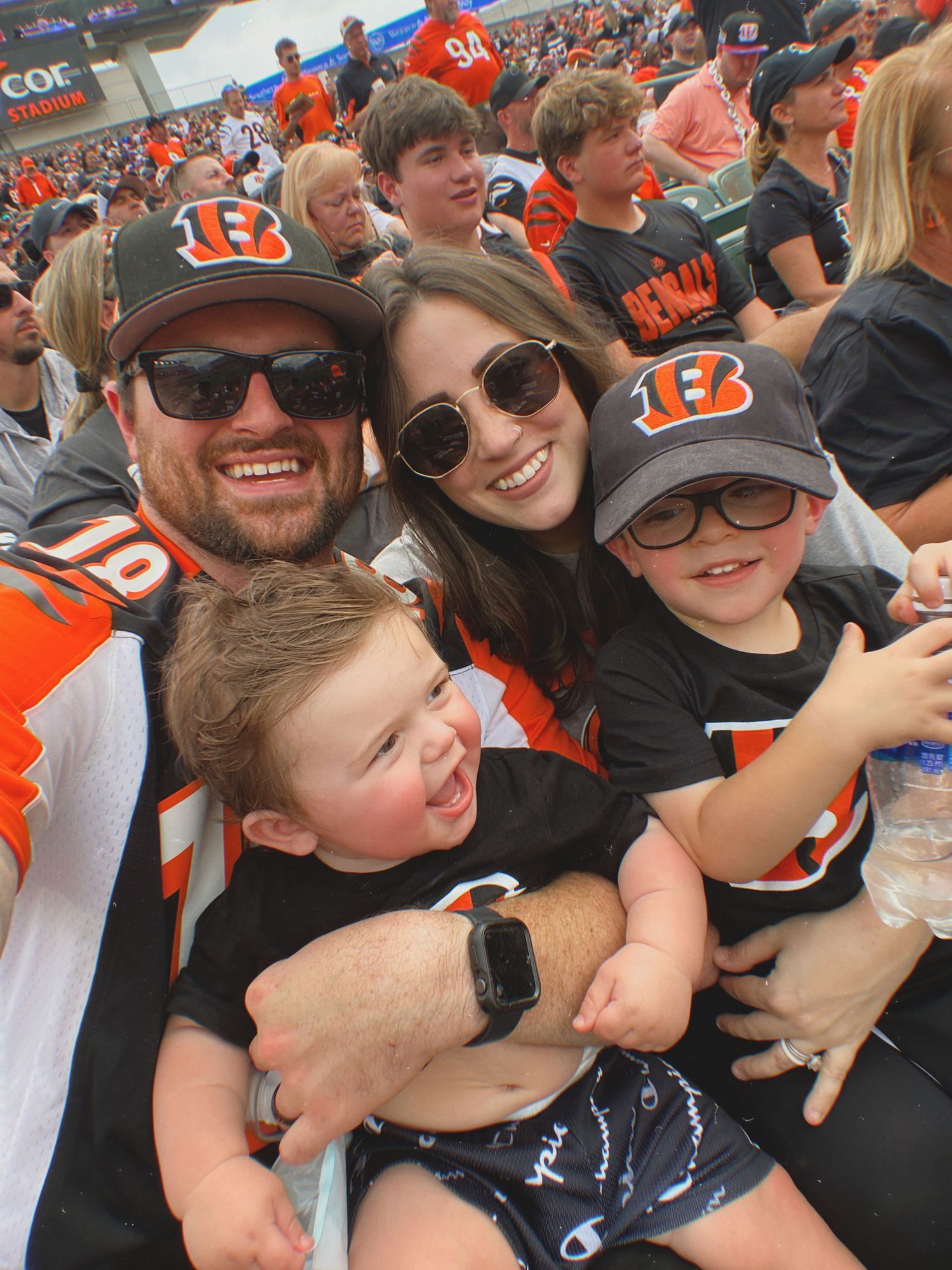 Cincinnati Bengals fans in orange and black team gear show support while enjoying a game at the stadium.