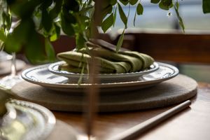 Elegant place settings with fresh greenery and white dinnerware at a wedding reception.