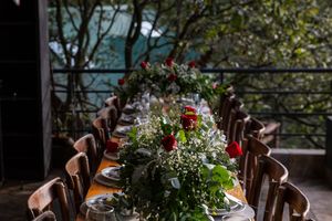 Wedding reception table settings with floral centerpieces and rustic wooden chairs.