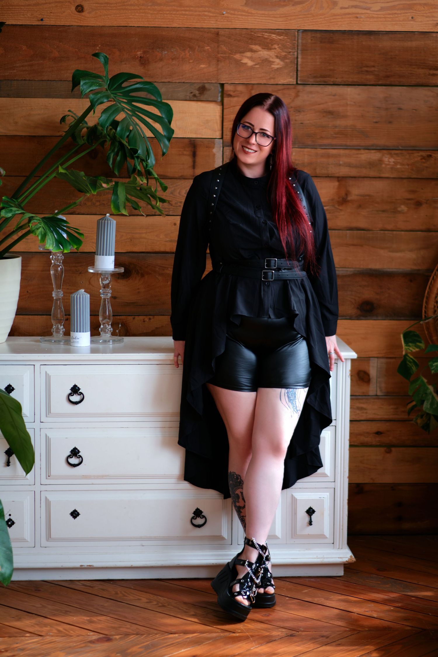 Alternative style portrait with bright red hair, glasses and black outfit.