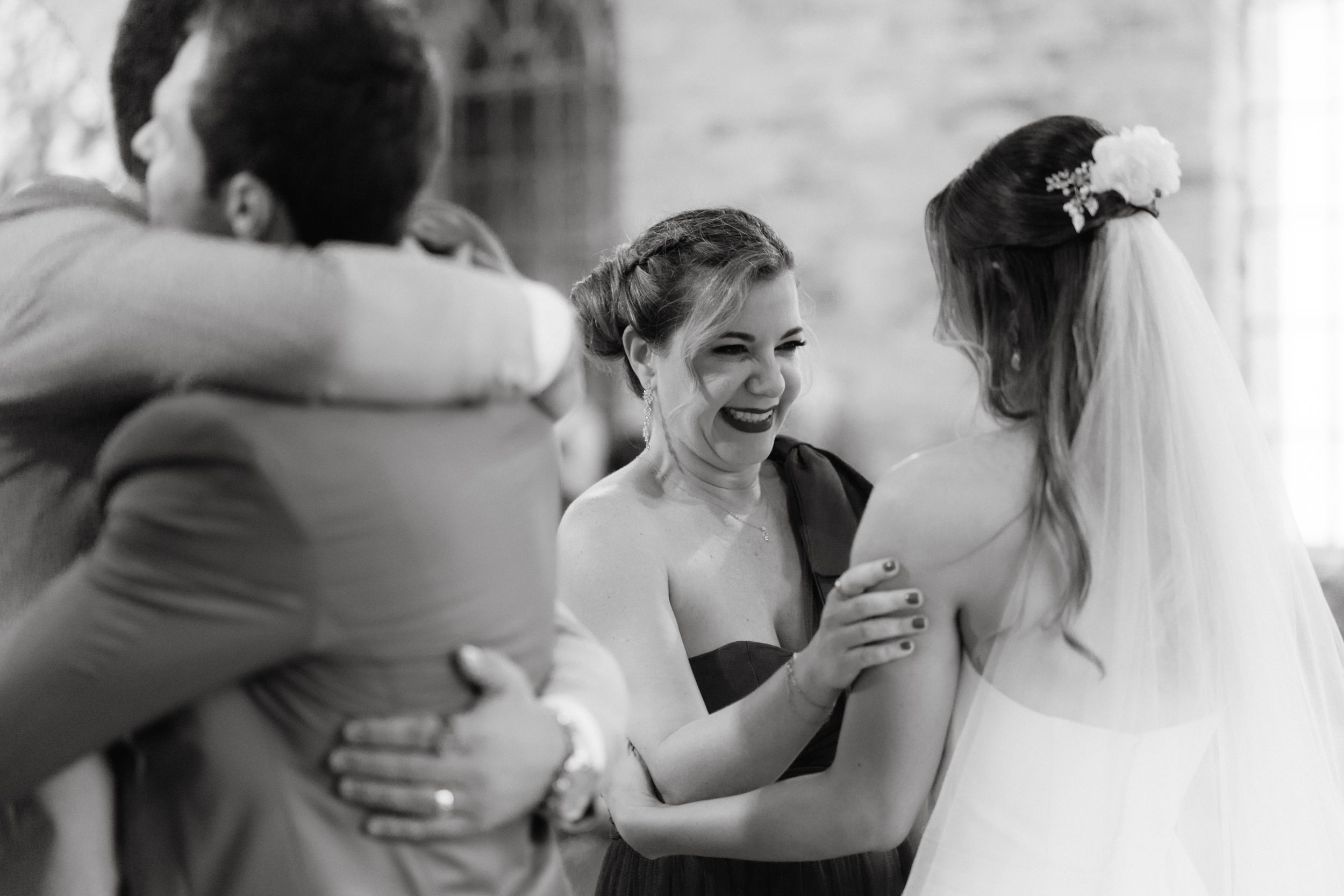Black and white capture of emotional wedding party embraces and reactions during ceremony.