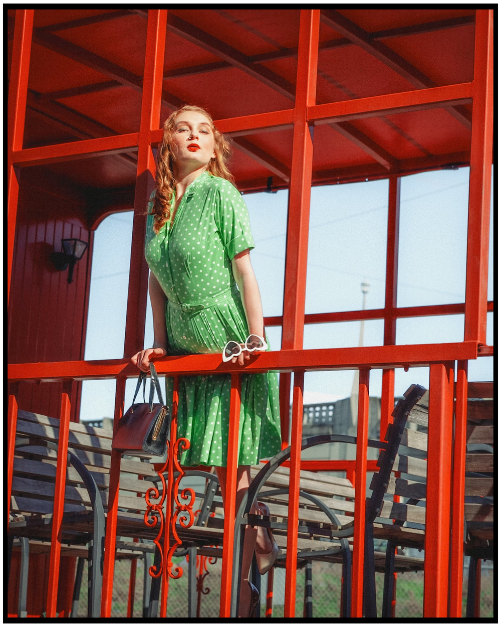 Retro-styled fashion photo of someone in a polka dot green dress on a red balcony. Portland portrait photographer